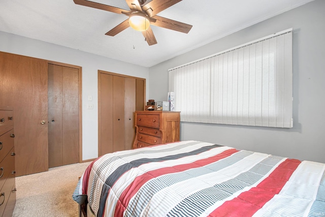 carpeted bedroom with ceiling fan and two closets