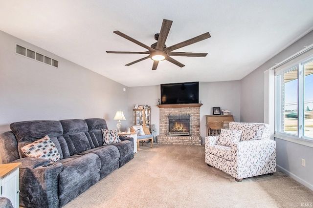 living area featuring light carpet, a fireplace, visible vents, and a ceiling fan