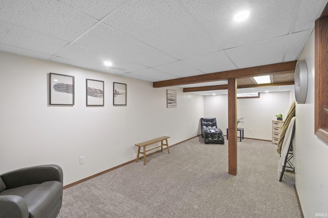 finished below grade area featuring light carpet, a paneled ceiling, and baseboards