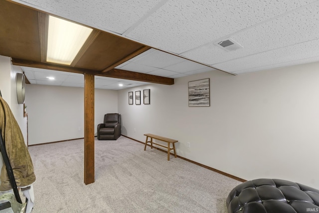 finished basement with light carpet, visible vents, baseboards, and a paneled ceiling