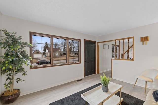 living area featuring visible vents, baseboards, and wood finished floors