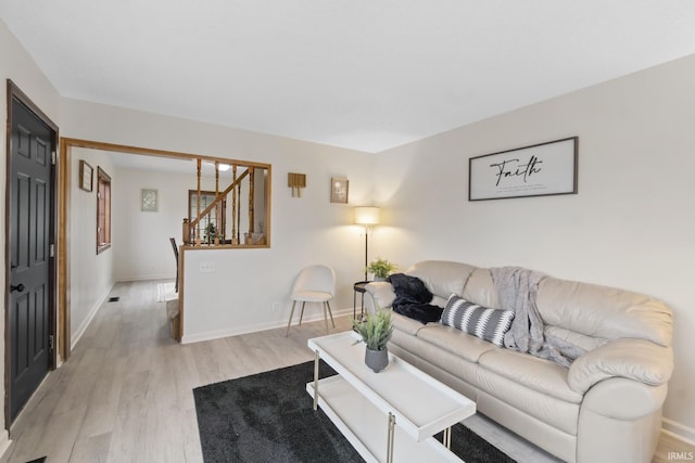 living area featuring visible vents, baseboards, stairway, and light wood finished floors