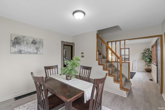 dining room featuring stairs, wood finished floors, visible vents, and baseboards