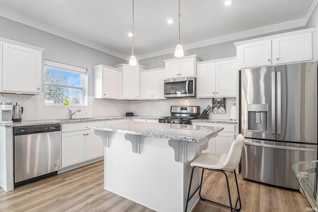 kitchen with a center island, a breakfast bar area, stainless steel appliances, white cabinetry, and a sink