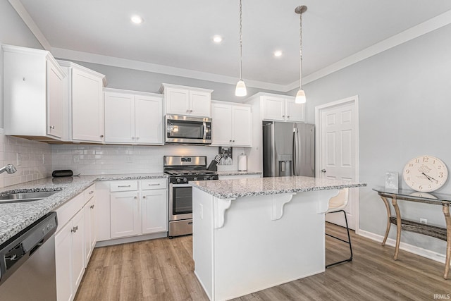 kitchen with light wood-style flooring, stainless steel appliances, a sink, white cabinets, and tasteful backsplash