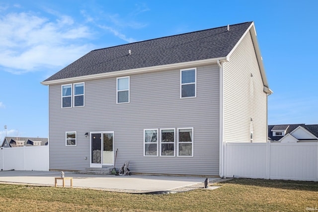 rear view of property with entry steps, fence, a yard, roof with shingles, and a patio area