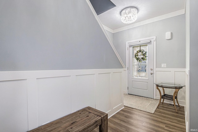 entryway with crown molding, a notable chandelier, visible vents, wainscoting, and wood finished floors