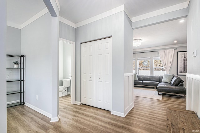 hall with baseboards, wood finished floors, and ornamental molding