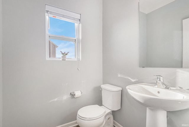 half bath with a sink, toilet, and baseboards