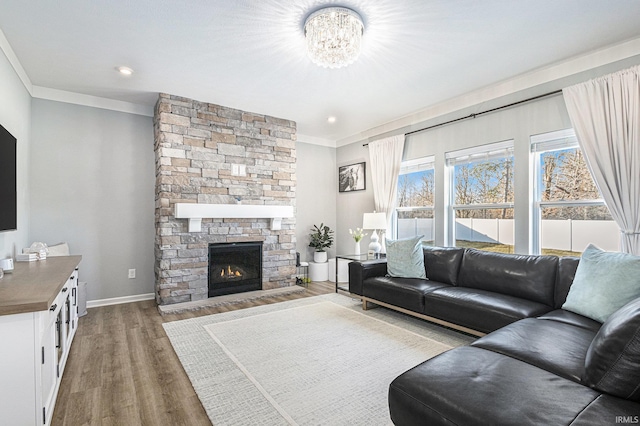 living area with a notable chandelier, a fireplace, wood finished floors, baseboards, and crown molding