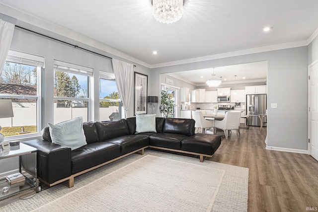 living area featuring crown molding, baseboards, a notable chandelier, and wood finished floors