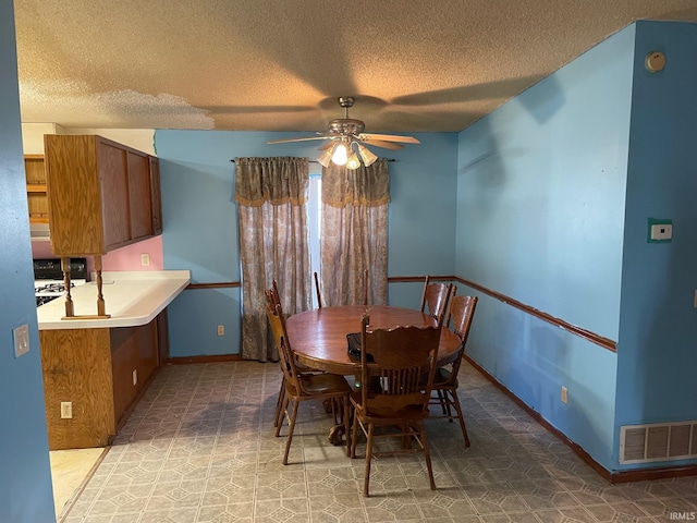 dining room with visible vents, a textured ceiling, a ceiling fan, and baseboards