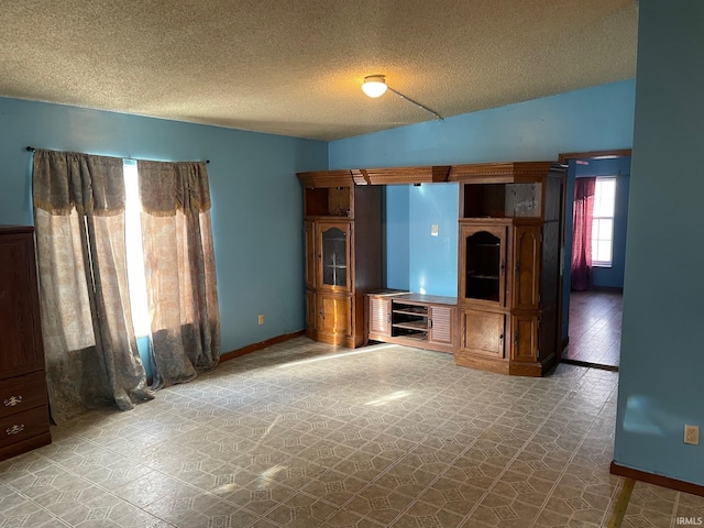 unfurnished living room featuring lofted ceiling, a textured ceiling, baseboards, and tile patterned floors