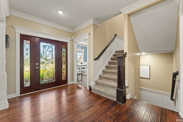 foyer entrance with hardwood / wood-style flooring, crown molding, visible vents, wainscoting, and stairs