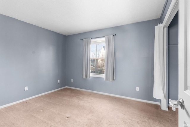 empty room featuring carpet and baseboards