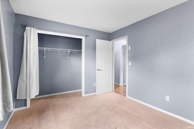 unfurnished bedroom with carpet, a closet, and baseboards