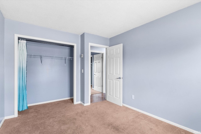 unfurnished bedroom featuring a closet, baseboards, and carpet flooring