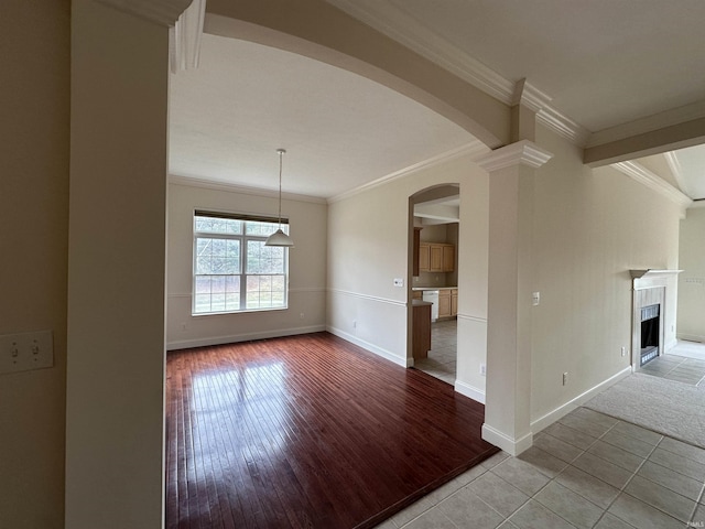 unfurnished living room with light wood-style flooring, a fireplace, arched walkways, and crown molding