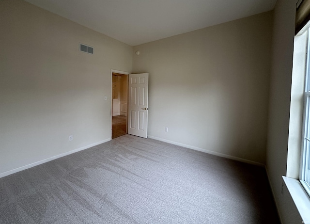 carpeted spare room with visible vents and baseboards