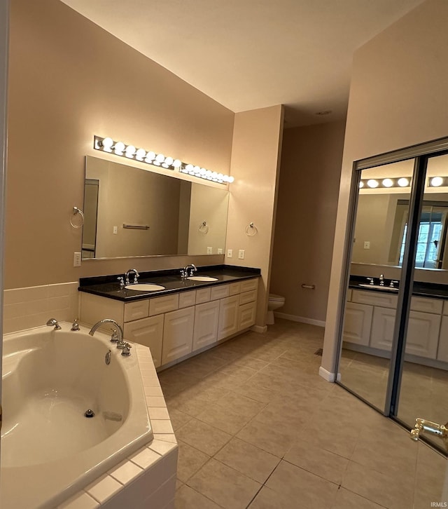 full bathroom featuring toilet, vanity, tile patterned flooring, baseboards, and a bath