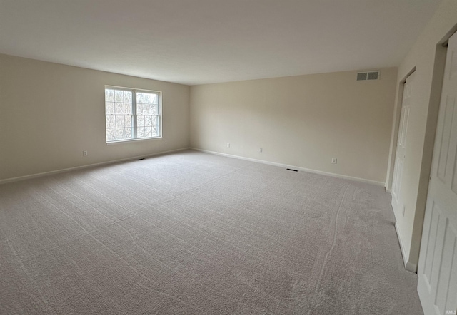 empty room featuring carpet floors, baseboards, and visible vents