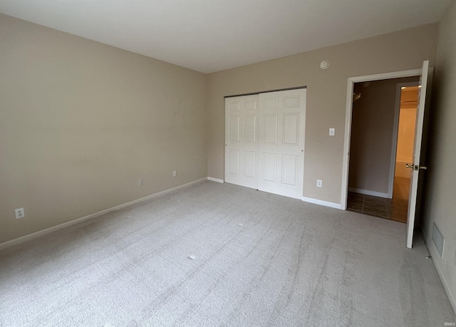 unfurnished bedroom featuring baseboards, a closet, and carpet flooring