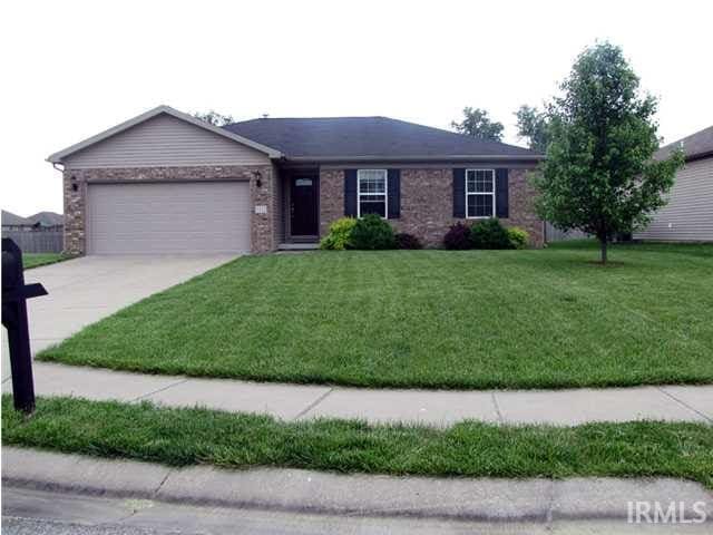 ranch-style house with a garage, brick siding, concrete driveway, and a front yard