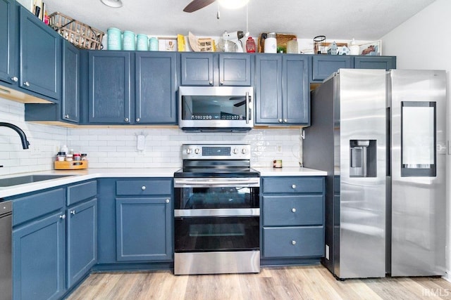 kitchen featuring blue cabinetry, appliances with stainless steel finishes, light countertops, and a sink