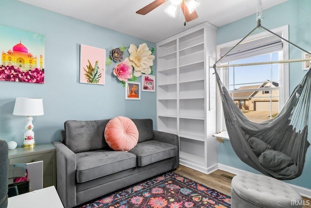 living area with visible vents, baseboards, wood finished floors, and a ceiling fan