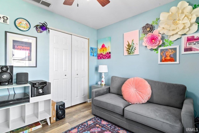 living room featuring visible vents, wood finished floors, and a ceiling fan