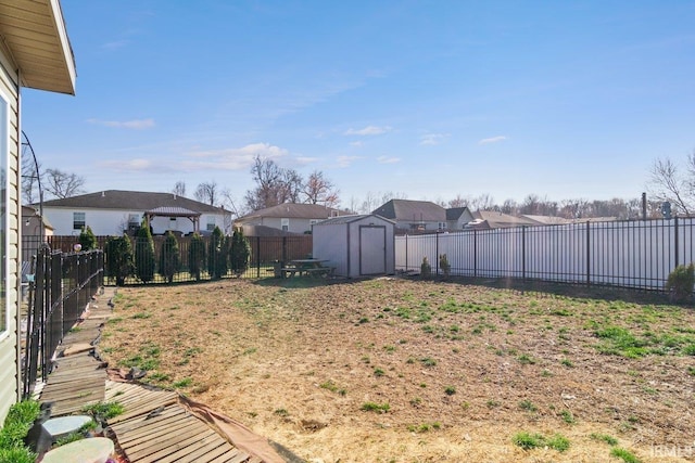 view of yard with an outbuilding, a residential view, a storage shed, and a fenced backyard