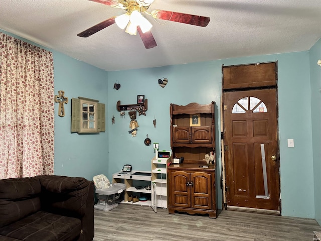 interior space featuring ceiling fan, a textured ceiling, and wood finished floors