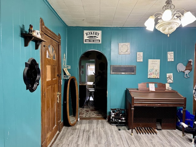 interior space with arched walkways, wood finished floors, and an inviting chandelier