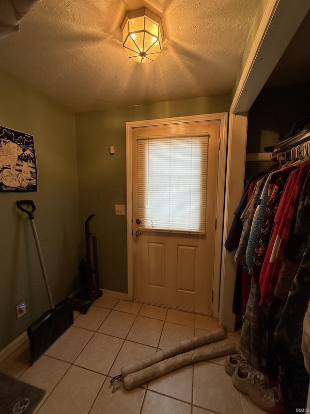 doorway to outside with a textured ceiling and light tile patterned flooring