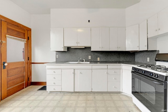 kitchen featuring light floors, backsplash, gas stove, and a sink