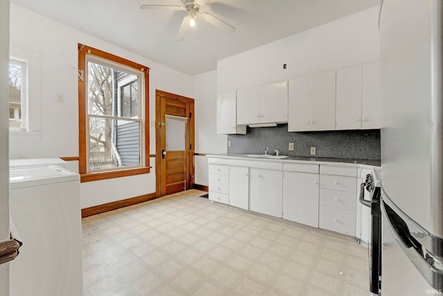 kitchen with light floors, decorative backsplash, freestanding refrigerator, white cabinetry, and a sink