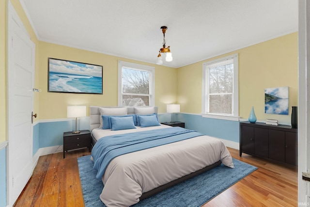 bedroom featuring ornamental molding, multiple windows, wood finished floors, and baseboards