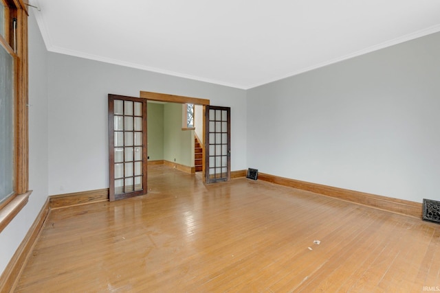 empty room with french doors, crown molding, stairway, wood finished floors, and baseboards