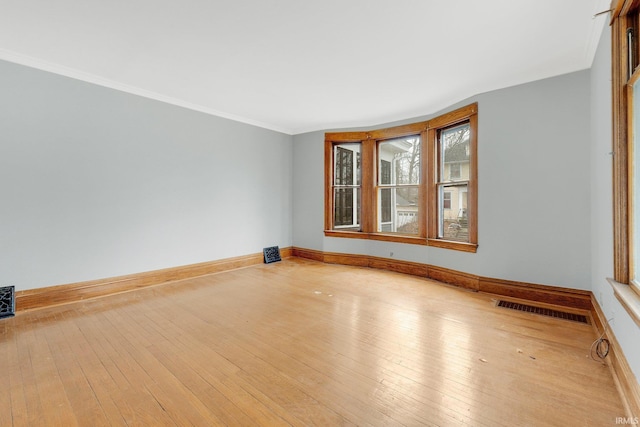 spare room with baseboards, visible vents, hardwood / wood-style floors, and ornamental molding