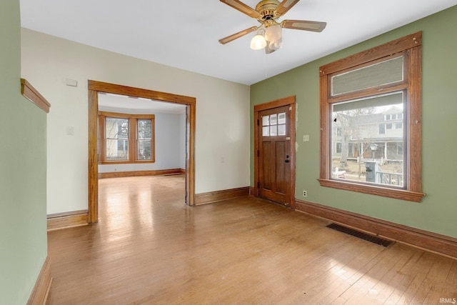 foyer entrance featuring light wood-style floors, baseboards, visible vents, and a ceiling fan