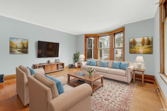 living room featuring baseboards, light wood-style flooring, and crown molding