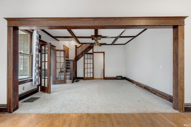 empty room with baseboards, visible vents, coffered ceiling, hardwood / wood-style floors, and stairs