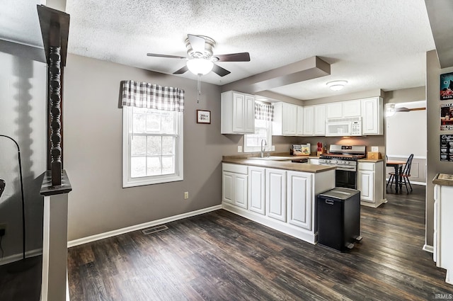 kitchen featuring stainless steel range with gas cooktop, dark wood finished floors, a sink, and white microwave