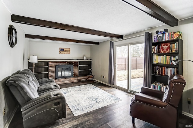 living room with beamed ceiling, a brick fireplace, wood finished floors, and baseboards