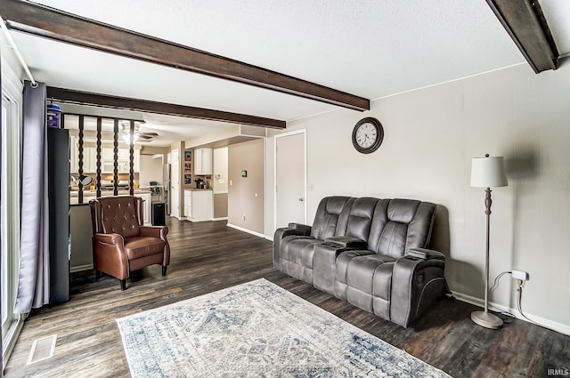 living area featuring beamed ceiling, wood finished floors, and baseboards