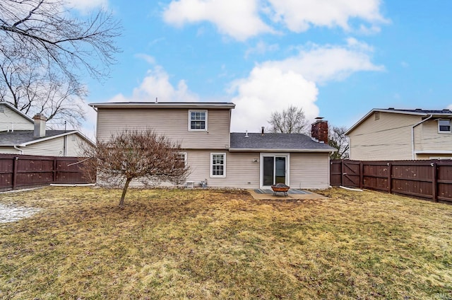 rear view of house featuring a patio area, a fenced backyard, a chimney, and a yard