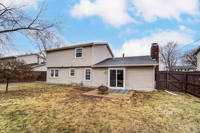 rear view of house featuring a patio, an outdoor fire pit, fence, a lawn, and a chimney