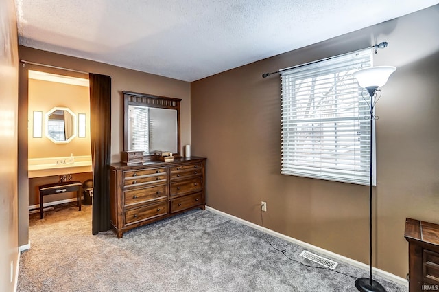 bedroom with light carpet, baseboards, visible vents, ensuite bathroom, and a textured ceiling