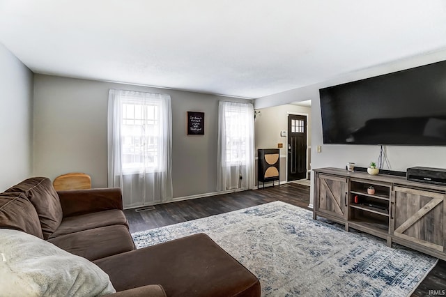 living room with visible vents, baseboards, and wood finished floors