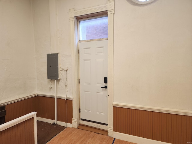 entryway with electric panel, a wainscoted wall, wood walls, and wood finished floors